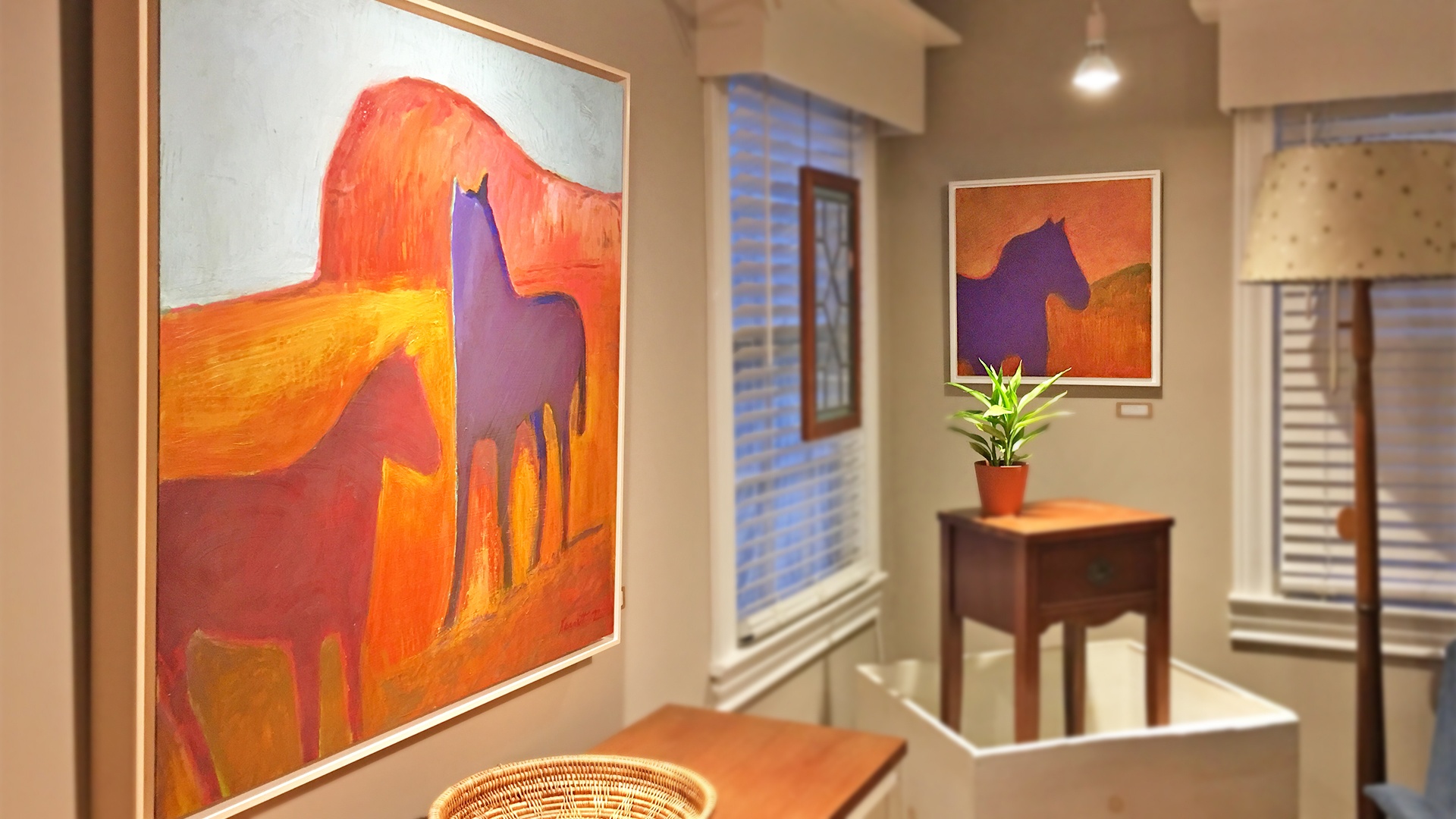 Art gallery in greenville sc shows large painting in a home setting of horses with bright red and purple colors by artist Phil Garrett.
